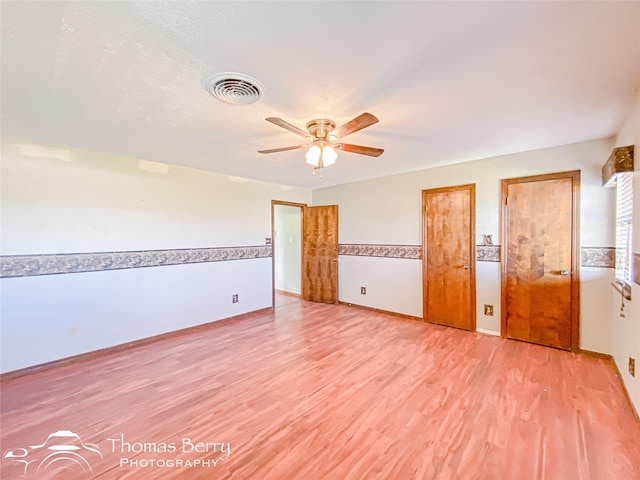 unfurnished bedroom featuring two closets, ceiling fan, and light hardwood / wood-style flooring