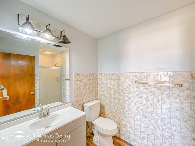 bathroom featuring tile walls, vanity, toilet, and walk in shower