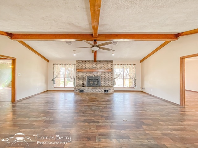 unfurnished living room with a textured ceiling, vaulted ceiling with beams, and a wealth of natural light