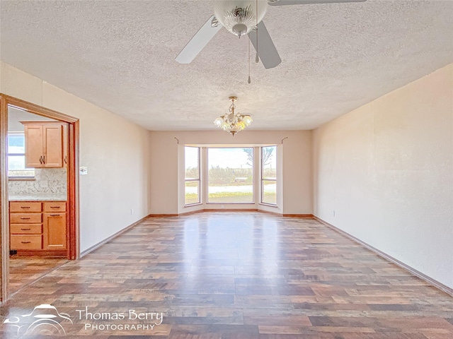 spare room featuring hardwood / wood-style floors, ceiling fan with notable chandelier, and a textured ceiling