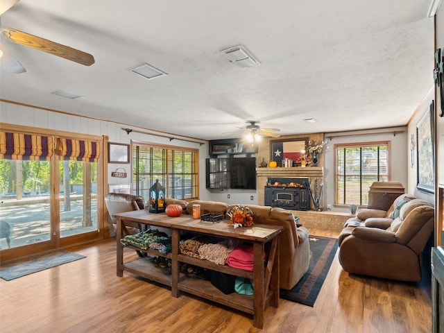 living room featuring ceiling fan, a textured ceiling, and light wood-type flooring