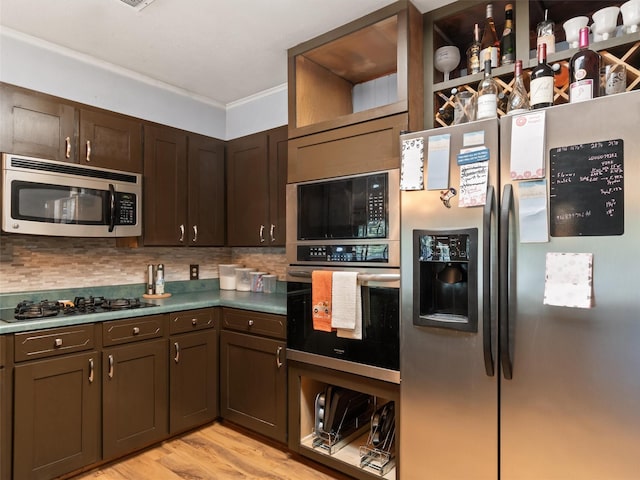 kitchen featuring appliances with stainless steel finishes, dark brown cabinets, backsplash, and light wood-type flooring