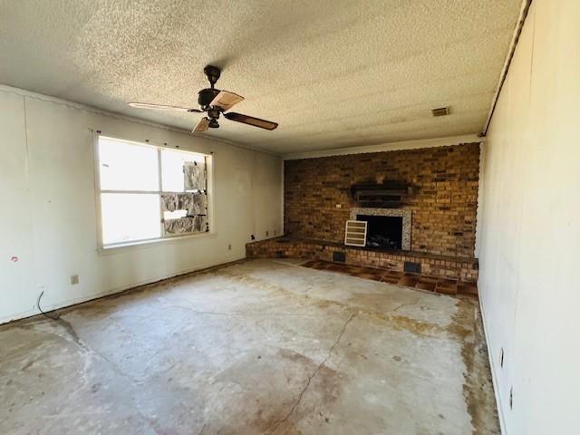 unfurnished living room featuring ceiling fan, a fireplace, concrete flooring, and a textured ceiling