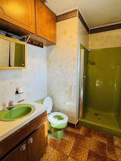 bathroom featuring vanity, toilet, a textured ceiling, and tiled shower