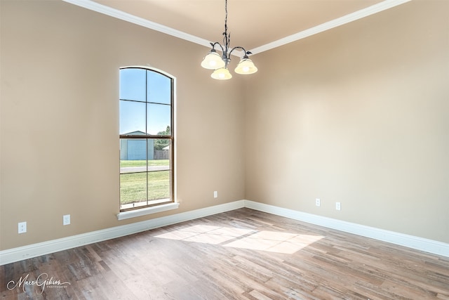 unfurnished room featuring an inviting chandelier, ornamental molding, and light wood-type flooring