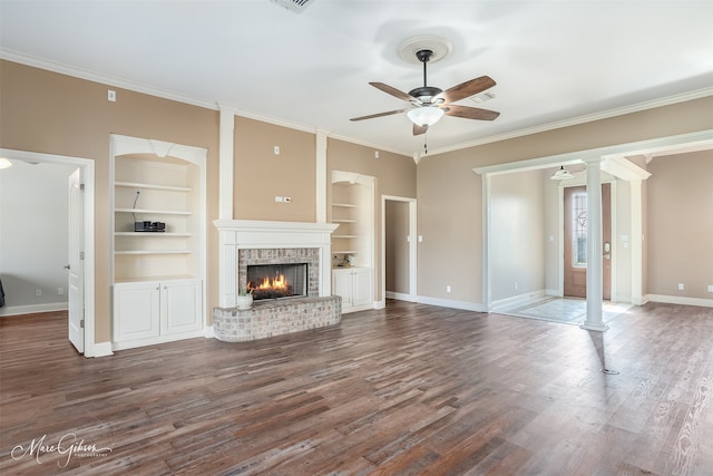 unfurnished living room with ornate columns, ornamental molding, a brick fireplace, and dark hardwood / wood-style floors