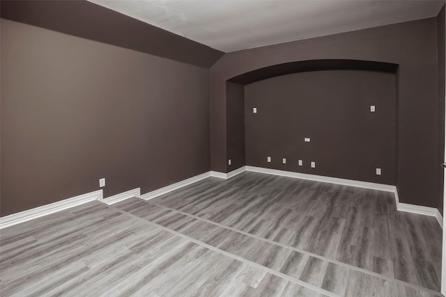 empty room with wood-type flooring and vaulted ceiling