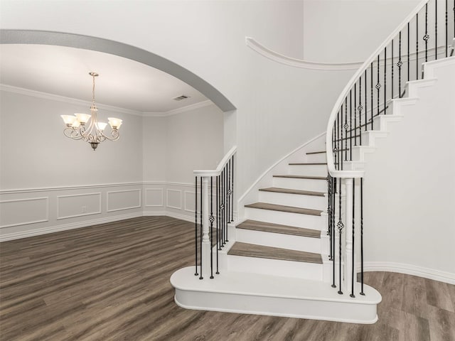 staircase with crown molding, hardwood / wood-style floors, and a chandelier