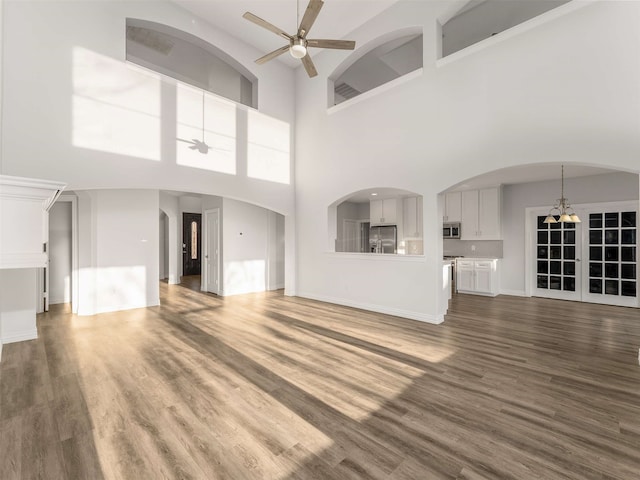 unfurnished living room with dark hardwood / wood-style floors and ceiling fan with notable chandelier