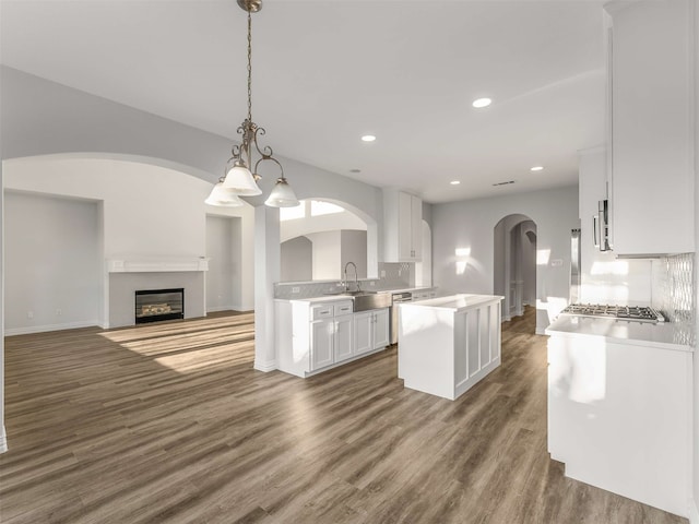 kitchen featuring sink, appliances with stainless steel finishes, white cabinetry, hanging light fixtures, and a center island