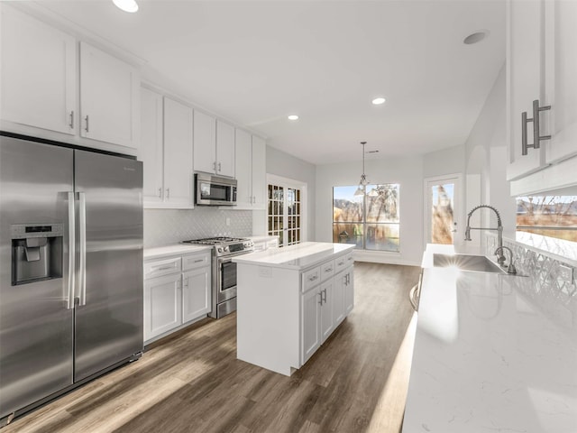 kitchen featuring sink, a kitchen island, pendant lighting, stainless steel appliances, and white cabinets