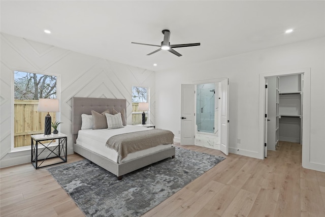 bedroom featuring multiple windows, a spacious closet, light hardwood / wood-style flooring, and ceiling fan