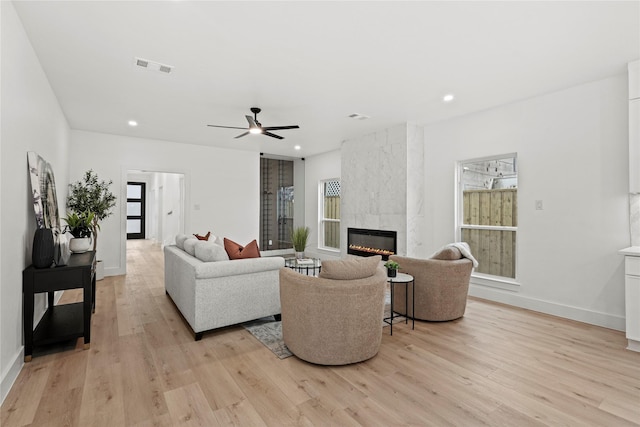 living room featuring ceiling fan, a fireplace, and light hardwood / wood-style flooring