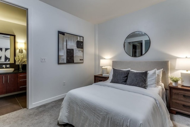 carpeted bedroom with ensuite bathroom and sink