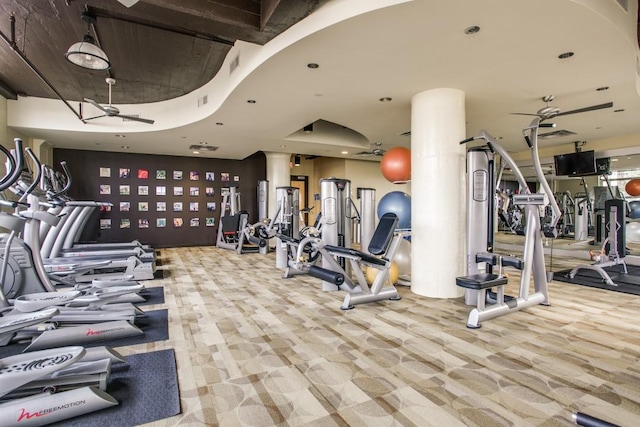 exercise room featuring light carpet, ceiling fan, and ornate columns