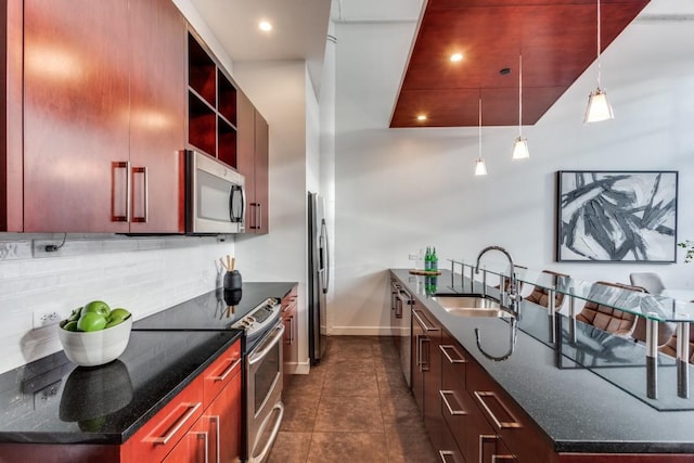 kitchen featuring sink, dark tile patterned floors, appliances with stainless steel finishes, hanging light fixtures, and decorative backsplash