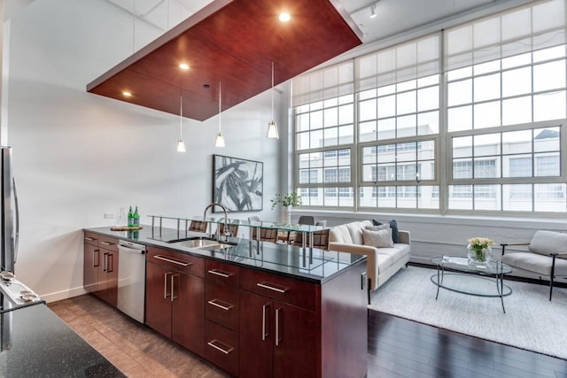 kitchen with pendant lighting, sink, dark wood-type flooring, appliances with stainless steel finishes, and kitchen peninsula