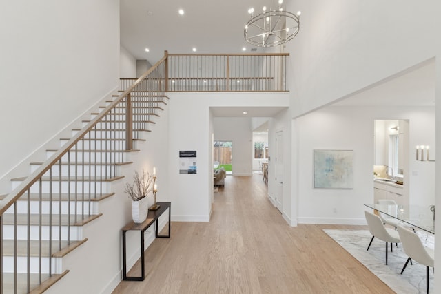 entrance foyer with a high ceiling, a notable chandelier, and light wood-type flooring