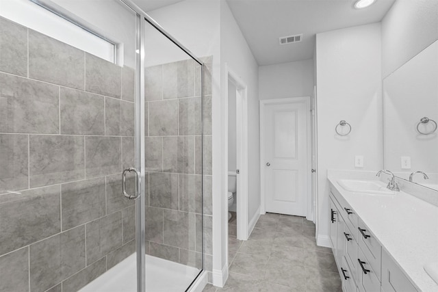 bathroom featuring tile patterned floors, vanity, toilet, and a shower with door