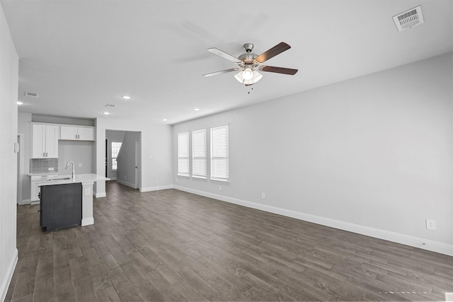 unfurnished living room with sink, dark hardwood / wood-style floors, and ceiling fan