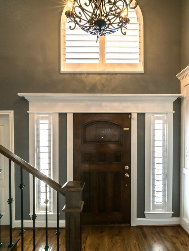 foyer entrance with an inviting chandelier and dark wood-type flooring