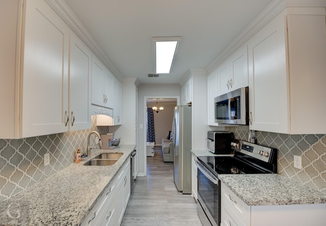 kitchen featuring stainless steel appliances, sink, white cabinets, and light stone counters