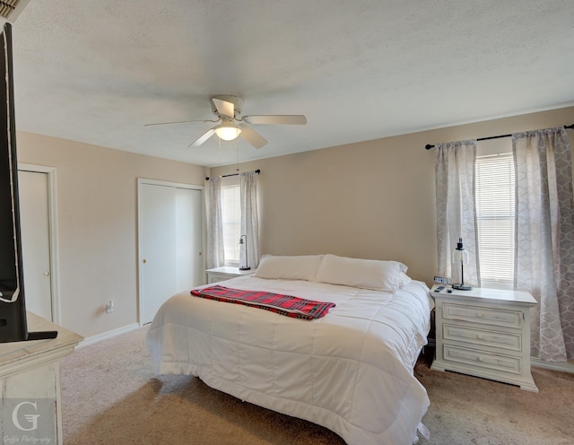 bedroom featuring a textured ceiling, light colored carpet, and ceiling fan