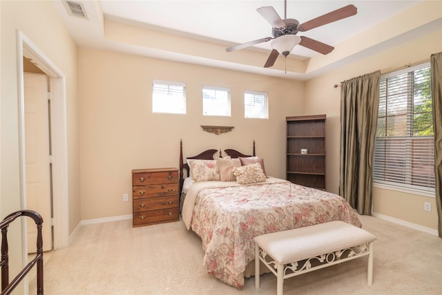 bedroom featuring ceiling fan, light colored carpet, and a raised ceiling