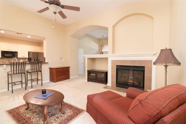 carpeted living room featuring ceiling fan and a tile fireplace