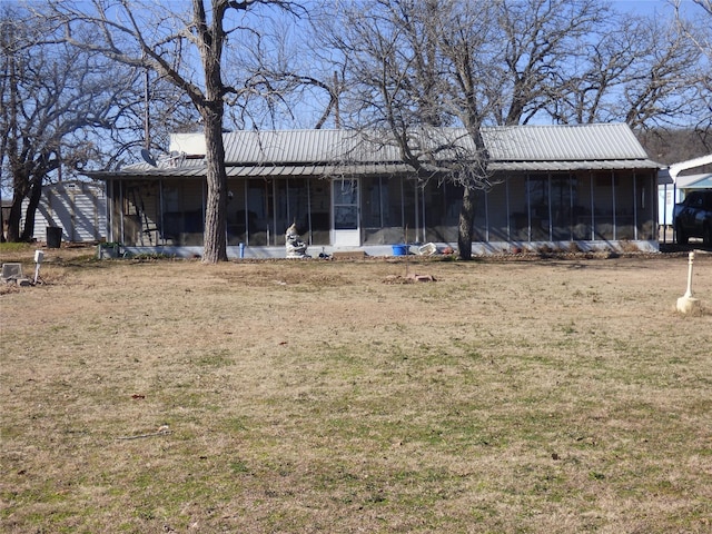 back of property featuring metal roof, a yard, and a sunroom