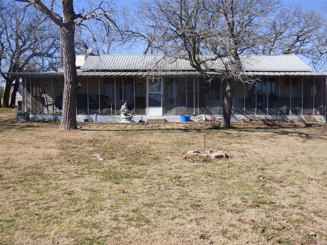 back of property with a sunroom, a yard, and metal roof