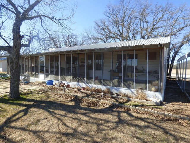 rear view of house with a sunroom and metal roof