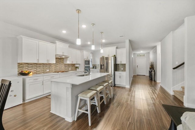 kitchen featuring appliances with stainless steel finishes, sink, a center island with sink, and white cabinets