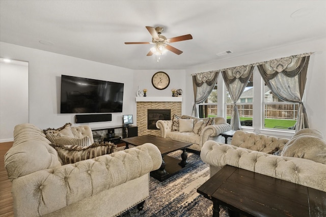 living room with a stone fireplace, hardwood / wood-style floors, and ceiling fan