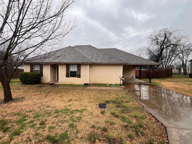 single story home featuring a shingled roof, fence, and a front lawn