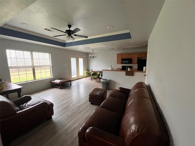 living room with visible vents, a raised ceiling, ceiling fan, wood finished floors, and french doors