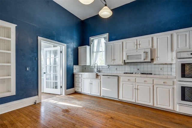 kitchen featuring white appliances, decorative light fixtures, sink, and white cabinets