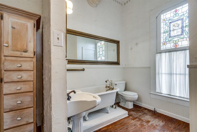 bathroom with toilet, hardwood / wood-style floors, and a tub