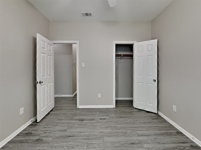 unfurnished bedroom featuring ceiling fan, light hardwood / wood-style floors, and a closet