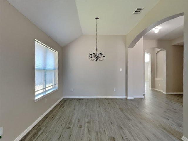 unfurnished dining area with an inviting chandelier, vaulted ceiling, and light hardwood / wood-style floors