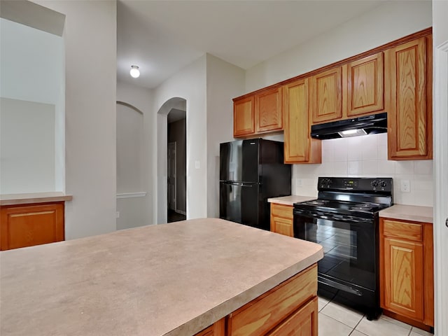 kitchen featuring tasteful backsplash, light tile patterned floors, and black appliances