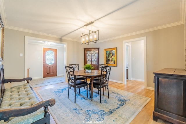 dining area with a notable chandelier, light hardwood / wood-style flooring, and ornamental molding