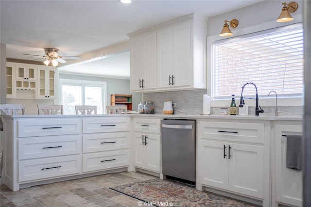 kitchen featuring tasteful backsplash, white cabinetry, dishwasher, ceiling fan, and kitchen peninsula