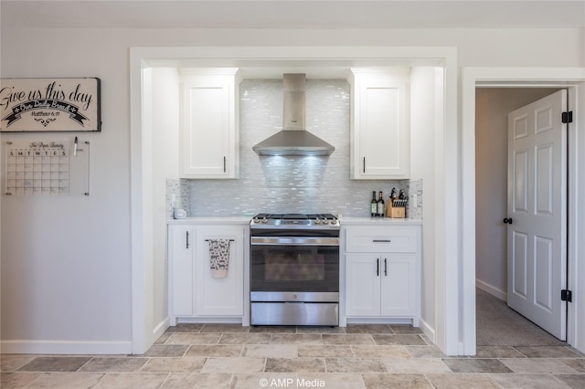 kitchen featuring tasteful backsplash, white cabinets, stainless steel gas stove, and wall chimney range hood