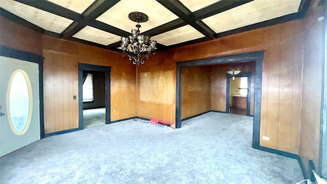 carpeted spare room featuring wooden walls, coffered ceiling, and beam ceiling