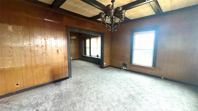 empty room featuring beam ceiling, carpet floors, and wood walls