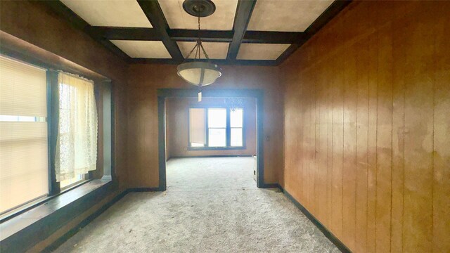 corridor featuring beamed ceiling, coffered ceiling, light carpet, and wood walls