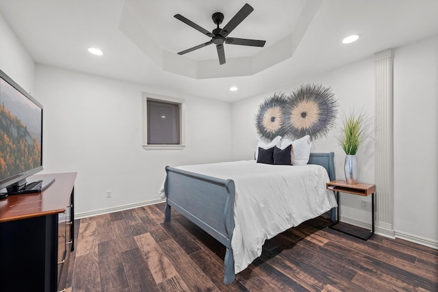 bedroom with a tray ceiling, dark hardwood / wood-style floors, and ceiling fan