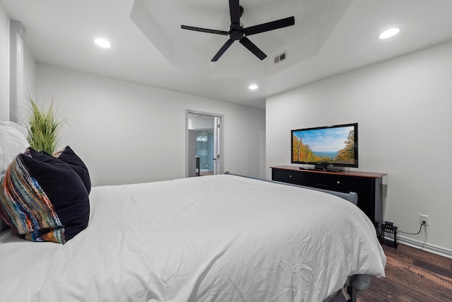 bedroom with a tray ceiling, dark hardwood / wood-style floors, and ceiling fan