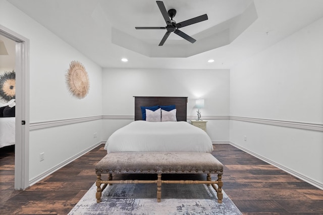 bedroom with dark wood-type flooring, ceiling fan, and a raised ceiling